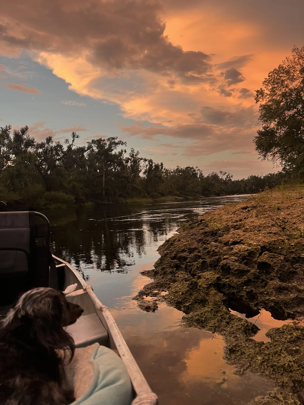 Canoe pulled along the Suwannee River at sunset with orange clouds reflected on the water